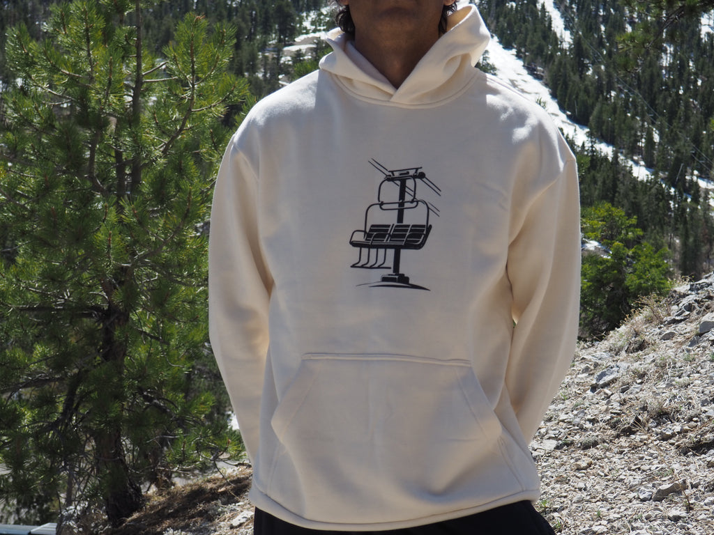 Person wearing a off white Chairlift Brag hoodie with a black graphic in a mountainous area